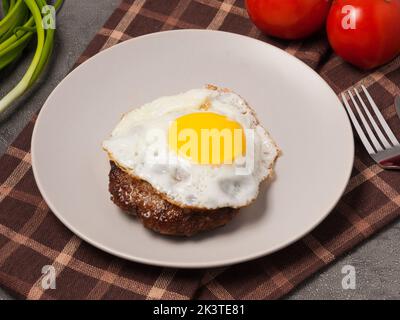 Leckeres, gehacktes Steak mit Fleisch, garniert mit Tomaten und grünen Zwiebeln Stockfoto