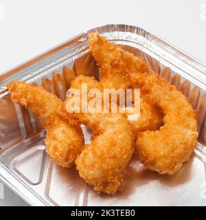 Leckere panierte Garnelen in einem Folienbehälter. Konzept: Lieferung von Lebensmitteln, schneller Snack Stockfoto