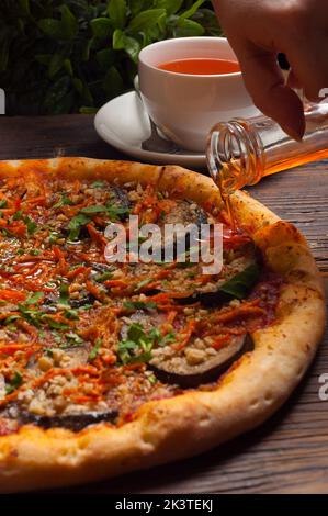 Das Mädchen gießt Auberginen leckere Pizza mit heißem Öl. Konzept: Vegetarismus Stockfoto