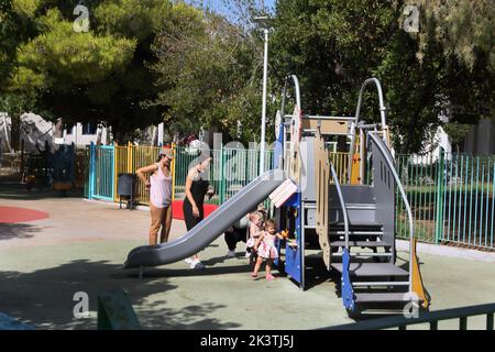 Vouliagmeni Athen Griechenland Thiseos Straße Spielplatz Familie spielt auf der Rutsche Stockfoto