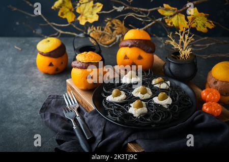 Halloween Party Jack-o-Laterne Schokolade orange Kuchen vor dem Hintergrund des alten Waldes, Äste und Blätter. Halloween-Food-Konzept. Süßigkeiten Stockfoto