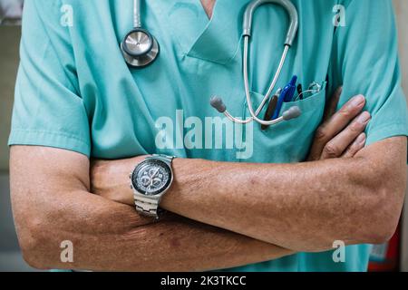 Nicht erkennbarer Mann, der während der Arbeit im Krankenhaus die Arme gefaltet hält Stockfoto