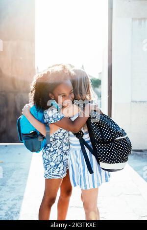 Lachende afroamerikanische Mädchen umarmen Freund auf der Straße in hellen Tag Stockfoto