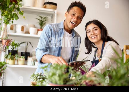 Inhaber von Kleinunternehmen betrachten die Kamera und halten dabei ein digitales Tablet Stockfoto