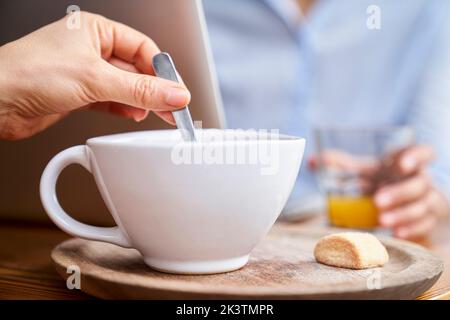 Nahaufnahme der Hand einer Frau, die Kaffee mit Löffel rührt Stockfoto