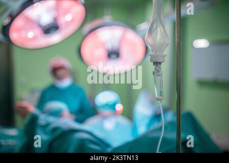 Tropfbeutel mit Anästhesiemedikament, der während der Operation auf dem unscharfen Hintergrund des Operationssaals im Krankenhaus auf dem Stand aufgehängt wird Stockfoto
