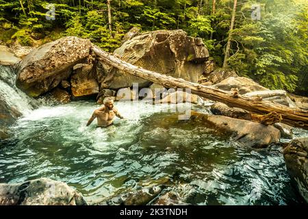 Hoher Winkel der männlichen Reisenden genießen kalte erfrischende sauberes Wasser des schmalen Bergflusses mit bewaldeten Ufer im Sommer Tag in den Pyrenäen Stockfoto