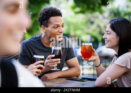 Lateinamerikanischer Mann, der mit Freunden ein Bier genießt Stockfoto