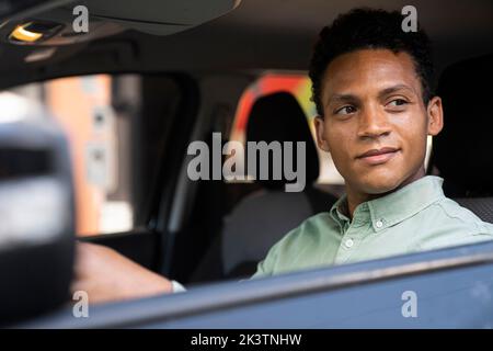 Mitte der Aufnahme eines schönen afroamerikanischen Geschäftsmannes in seinem Auto hinter dem Steuer, der zu seinem Büro fährt Stockfoto