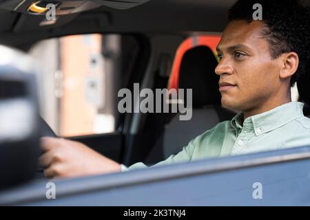 Seitenansicht des hübschen afroamerikanischen Mannes in seinem Auto, der zur Arbeit fährt Stockfoto