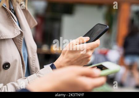 Nahaufnahme von Händen, die Smartphones halten, während sie im Freien arbeiten Stockfoto