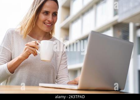 Aus der Perspektive der Unternehmerin, die auf den Laptop-Bildschirm schaut und Kaffee trinkt Stockfoto