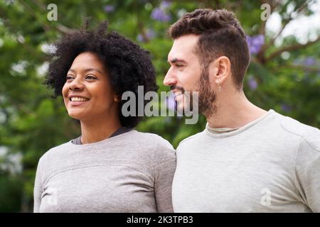 Mid-Shot-Porträt einer afroamerikanischen Frau und eines kaukasischen Mannes, der eine gute Zeit im Freien hat Stockfoto