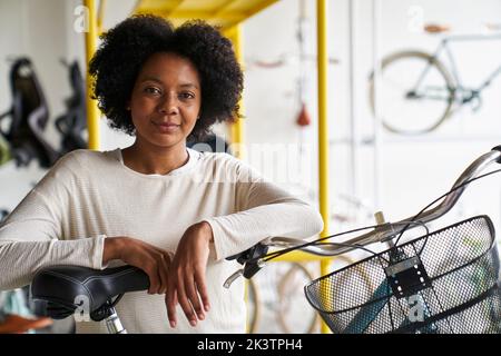 Porträt einer afroamerikanischen Ladenbesitzerin, die in ihrem Fahrradladen steht Stockfoto