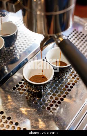 Von oben frisch aromatischer Kaffee im Fach an der Kaffeemaschine mit Kaffeebechern Stockfoto