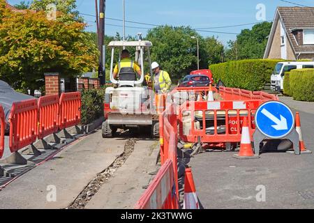 Red Road arbeitet Kunststoff-Sicherheitsbarrieren Beschränkung Hausbesitzer Zufahrt Mini-Bagger graben Breitband-Infrastruktur Graben in Bürgersteig Großbritannien Stockfoto