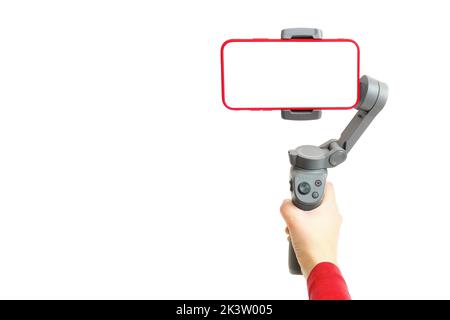 Die Hand hält einen 3-Achsen-Gimbal-Stabilisator, der Videoaufnahmen mit einem Smartphone macht. Modup-Vorlage. Stockfoto