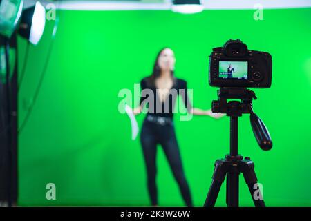 Ganzer Körper von weiblichen Moderatorin lesen Nachrichten auf Papier Dokument während der Aufzeichnung Programm für Social Media gegen Chromakey-Bildschirm Stockfoto