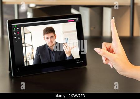 Webkonferenz. Geschäftskonflikt. Digitales Meeting. Professioneller Videoclip. Weibliche Exekutive Warnung mit Fingerbewegung männliche Angestellte auf Tablet-Bildschirm Stockfoto