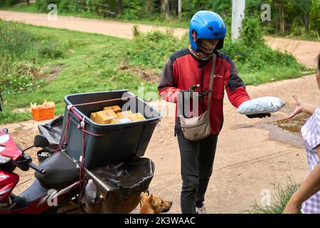 Ein Motorradkurier liefert Pakete in einem ländlichen Gebiet. Stockfoto