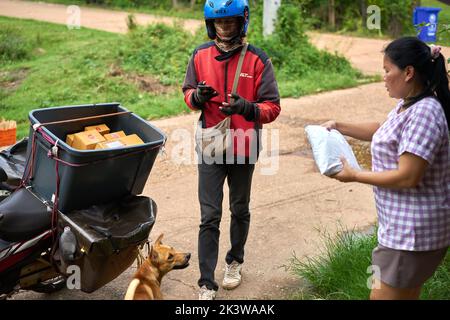 Ein Motorradkurier liefert Pakete in einem ländlichen Gebiet. Stockfoto