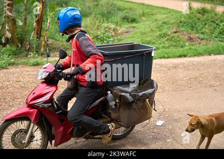 Ein Motorradkurier liefert Pakete in einem ländlichen Gebiet. Stockfoto