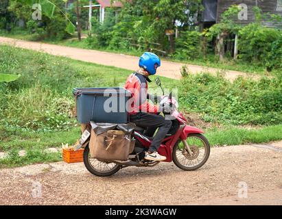 Ein Motorradkurier liefert Pakete in einem ländlichen Gebiet. Stockfoto