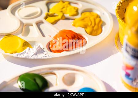 Die Farben und die Pinsel im Prozess der Arbeit, die Palette mit den gemischten Farben, alle Farben des Regenbogens in den Farben Stockfoto