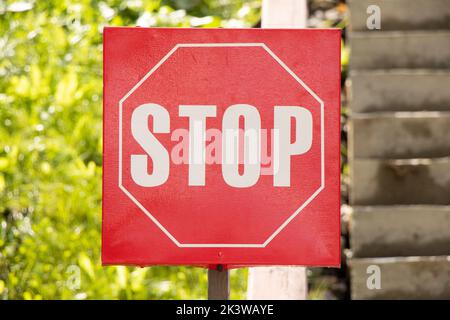 Stop-Schild auf einer roten Platte in der Nähe des Eingangs zum Park Nahaufnahme Stockfoto