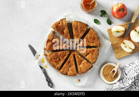 Frisch gebackene, köstliche Apfelkuchen, die in Stücke geschnitten werden, werden auf einem weißen Tisch serviert. Platz für Text Stockfoto