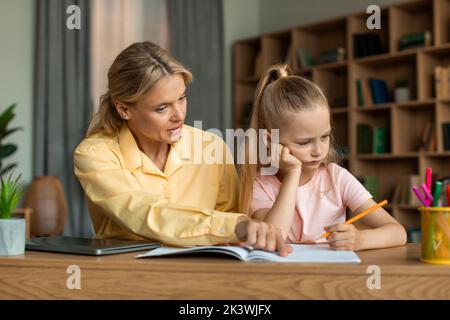 Strenge Mutter studiert mit kleinen Schulmädchen Tochter, schimpfen Vortrag für schlechte Noten, Mädchen unmotiviert, Hausaufgaben zu tun Stockfoto