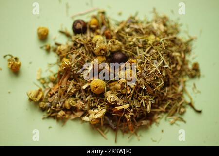 Teesammlung von trockenen Kräutern und Blumen auf grünem Tisch. Stockfoto