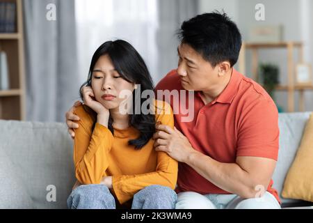 Liebevoller asiatischer Ehemann tröstet seine verärgerte Frau Stockfoto
