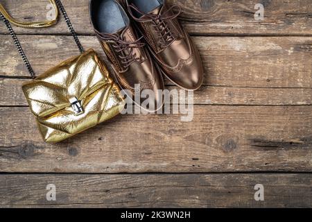 Herbst-Outfit für Damen. Set aus Schuhen und Tasche, weibliche Accessoires auf Holzhintergrund. Mode stilvolle Handtasche Kupplung, Glamour Schuhe. Speicherplatz kopieren Stockfoto