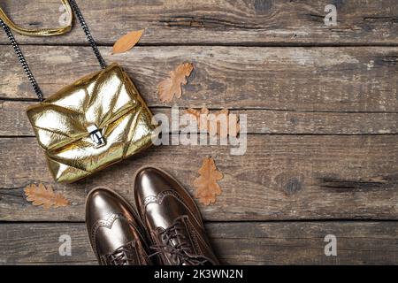 Herbst-Outfit für Damen. Set aus Schuhen und Tasche, weibliche Accessoires auf Holzhintergrund. Mode stilvolle Handtasche Kupplung, Glamour Schuhe. Speicherplatz kopieren Stockfoto