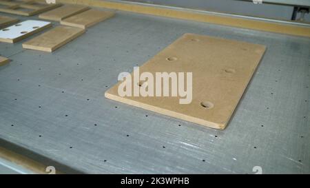 Weiße MDF-Platten liegen auf einem Tisch in einer Möbelfabrik. Auf dem Tisch befindet sich ein Stapel von OSB-Blättern. Baumaterial. OSB-Blätter werden gestapelt Stockfoto