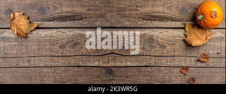 Festliches Herbstdekor aus Kürbissen und Herbstblättern auf rustikalem Holzhintergrund. Konzept des Erntedankfestes oder Halloween. Herbstkomposition mit CO Stockfoto