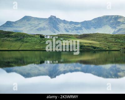 Spiegelungen eines kleinen Bauernhauses in den schottischen Highlands auf der Isle of Skye Stockfoto