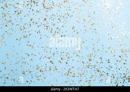 Goldenes Fliegen funkelt auf blauem Art und Weiseurlaub Hintergrund. Festlicher Hintergrund. Textur aus goldenem Glitzer auf Blau Stockfoto
