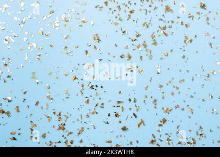 Goldenes Fliegen funkelt auf blauem Art und Weiseurlaub Hintergrund. Festlicher Hintergrund. Textur aus goldenem Glitzer auf Blau Stockfoto