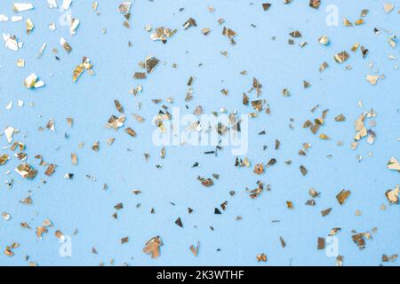 Goldenes Fliegen funkelt auf blauem Art und Weiseurlaub Hintergrund. Festlicher Hintergrund. Textur aus goldenem Glitzer auf Blau Stockfoto