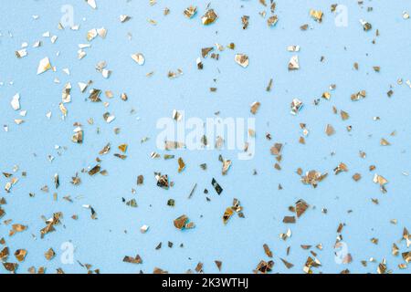 Goldenes Fliegen funkelt auf blauem Art und Weiseurlaub Hintergrund. Festlicher Hintergrund. Textur aus goldenem Glitzer auf Blau Stockfoto