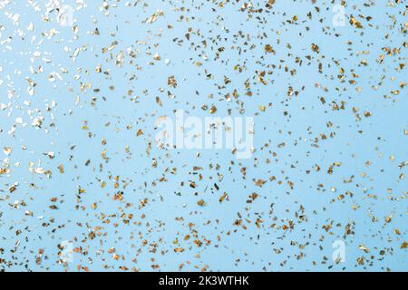 Goldenes Fliegen funkelt auf blauem Art und Weiseurlaub Hintergrund. Festlicher Hintergrund. Textur aus goldenem Glitzer auf Blau Stockfoto