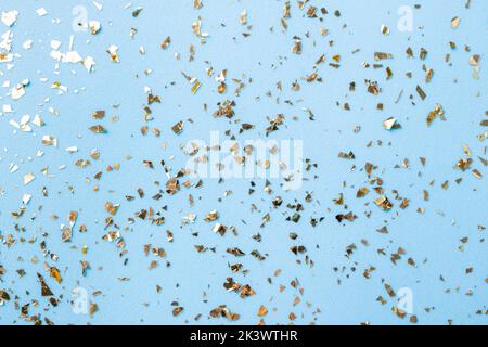 Goldenes Fliegen funkelt auf blauem Art und Weiseurlaub Hintergrund. Festlicher Hintergrund. Textur aus goldenem Glitzer auf Blau Stockfoto