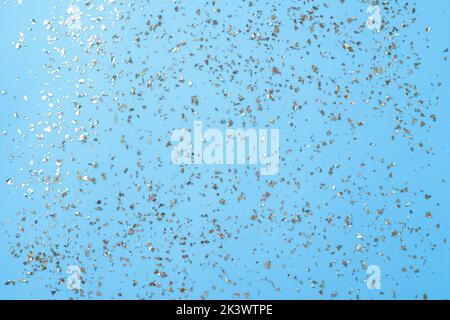 Goldenes Fliegen funkelt auf blauem Art und Weiseurlaub Hintergrund. Festlicher Hintergrund. Textur aus goldenem Glitzer auf Blau Stockfoto