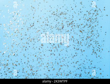 Goldenes Fliegen funkelt auf blauem Art und Weiseurlaub Hintergrund. Festlicher Hintergrund. Textur aus goldenem Glitzer auf Blau Stockfoto