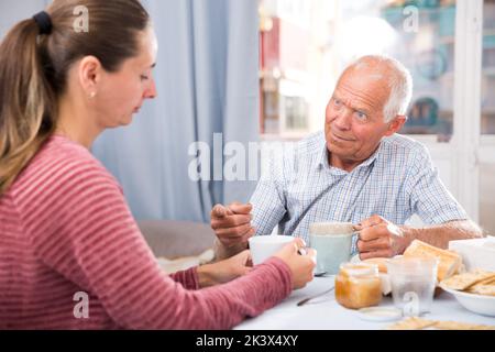 Älterer Mann, der mit einer jungen traurigen Tochter spricht und auf Fehler hinweist Stockfoto