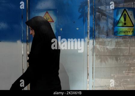 Teheran, Teheran, Iran. 28. September 2022. Eine verschleierte Frau geht in einer Straße in Teheran, Iran, 28. September 2022. Nach dem Tod von Masha Amini, einem 22-jährigen Mädchen, das am 13. September von der Polizeieinheit, die für die Durchsetzung der strengen iranischen Kleiderordnung für Frauen verantwortlich ist, festgenommen wurde, ist der Iran mit zahlreichen regierungsfeindlichen Protesten konfrontiert. Amini wurde am 16. September für tot erklärt, nachdem sie 3 Tage im Koma verbracht hatte. Während ihrer Beerdigung am 17. September brachen in Saqez, der Heimatstadt von Amini, erste Proteste aus. (Bild: © Rouzbeh Fouladi via ZUMA Press Wire) Stockfoto