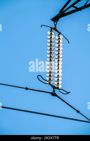 Isolatoren aus Glas an einer Hochspannungsleitung, an den Polen hängen sie als Aufhängevorrichtung zwischen dem Mast und dem stromführenden, nicht isolierten Kabel, ext Stockfoto