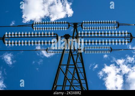 Isolatoren aus Glas an einer Hochspannungsleitung, an den Polen hängen sie als Aufhängevorrichtung zwischen dem Mast und dem stromführenden, nicht isolierten Kabel, ext Stockfoto